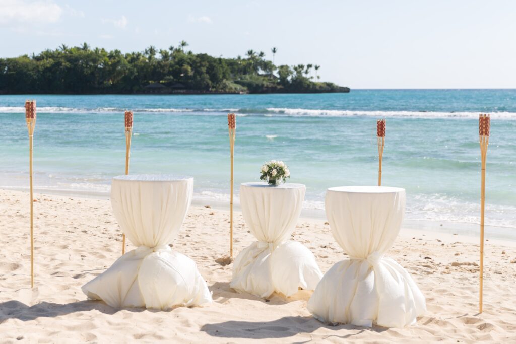 White linen cocktail tables and tiki torches on the beach