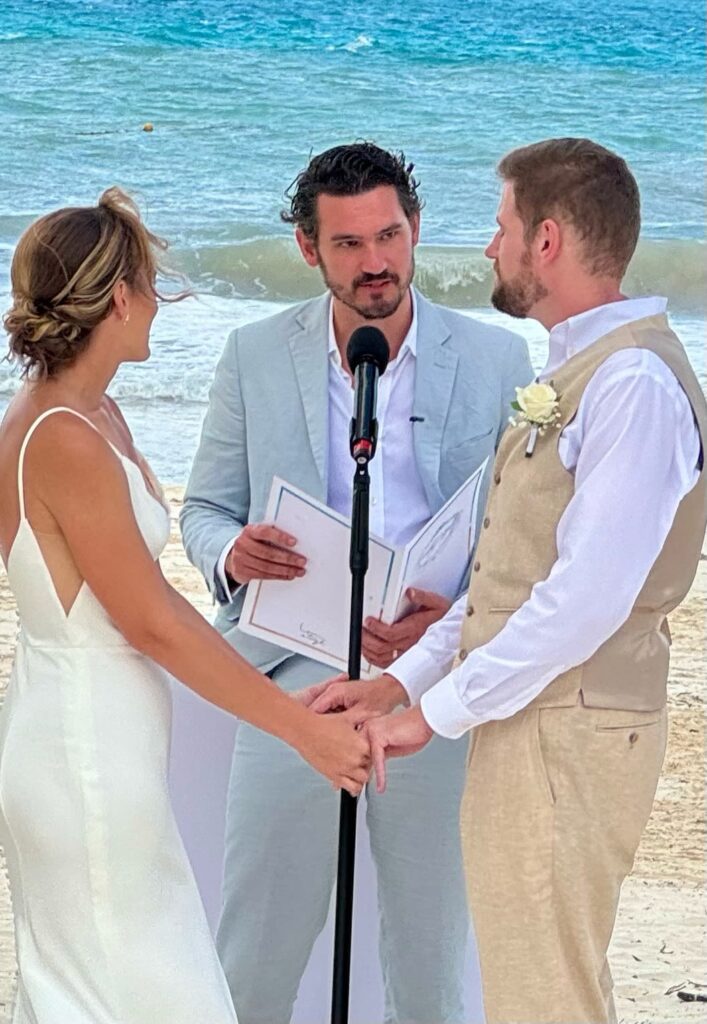 bride in white silk wedding dress and groom in tan wedding suit at beach wedding ceremony