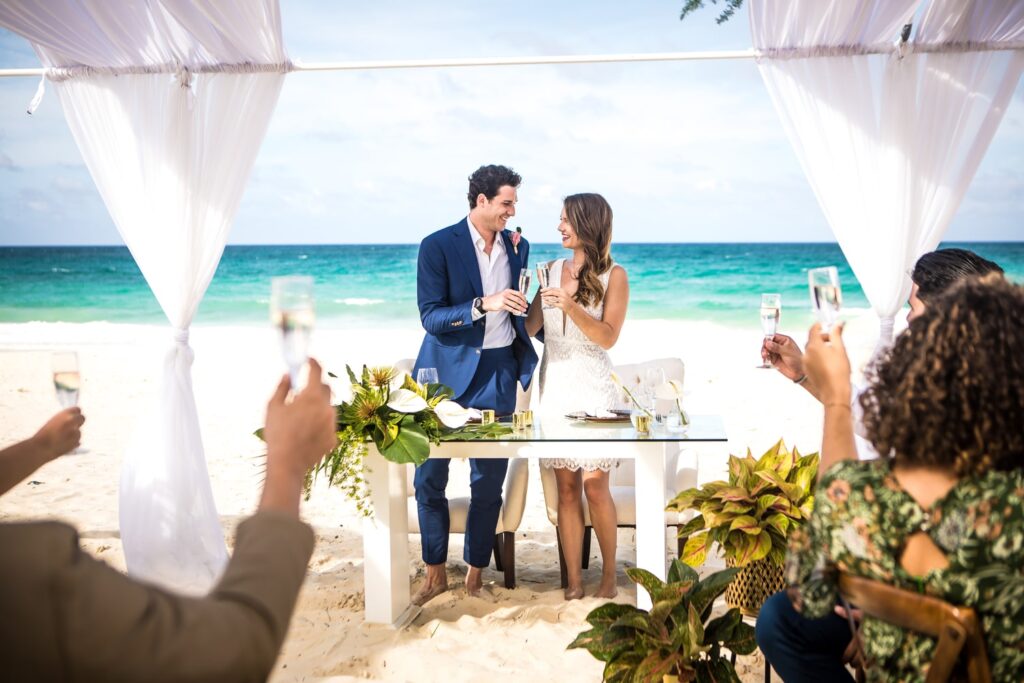 Bride and groom toast champagne during beach wedding reception