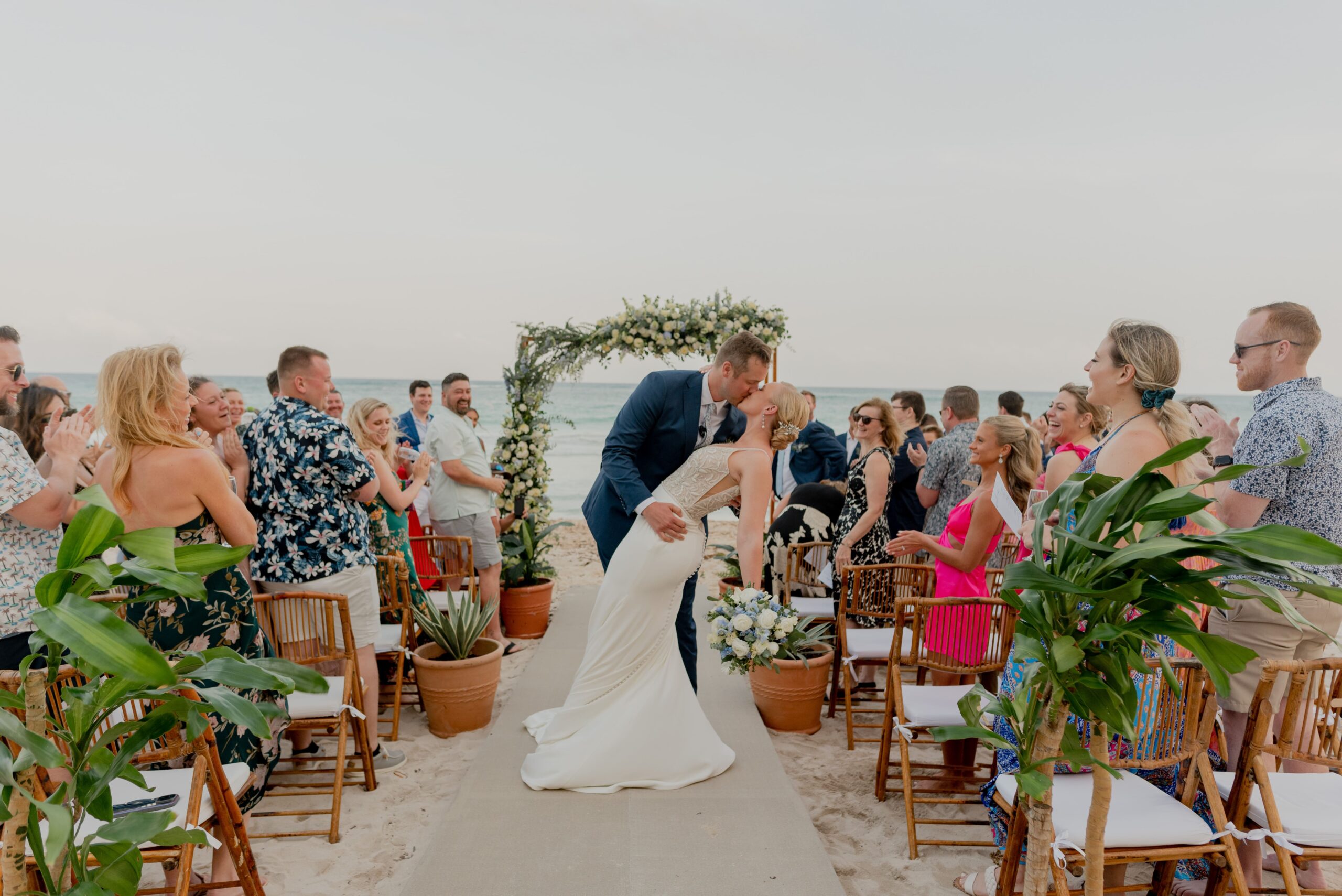 Bride and groom dipping and kissing during beach wedding ceremony