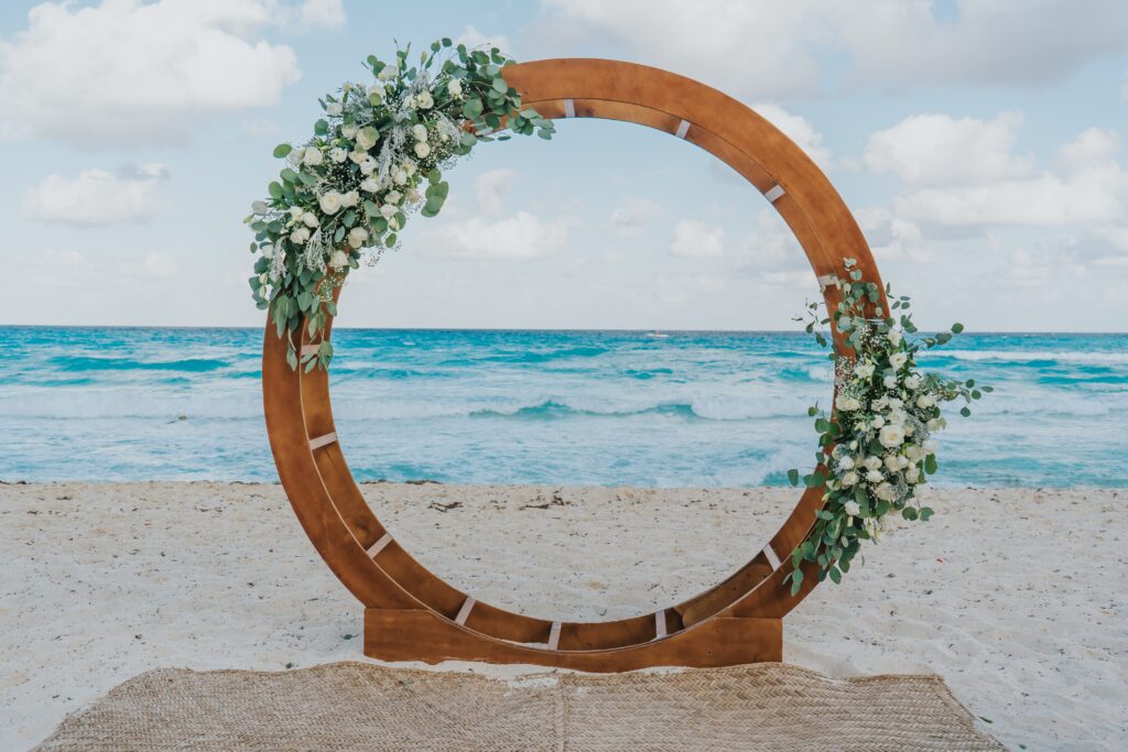 Beach wedding ceremony with circle wedding ceremony arch with white flowers