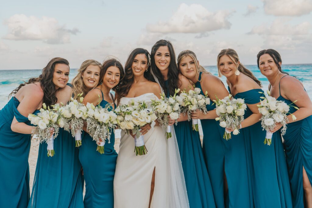 Bridesmaids in long blue bridesmaid dresses with white bouquets