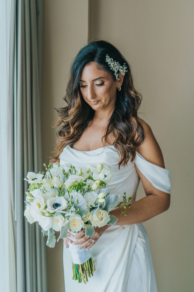 Bride holding white bridal bouquet in white ruched wedding dress