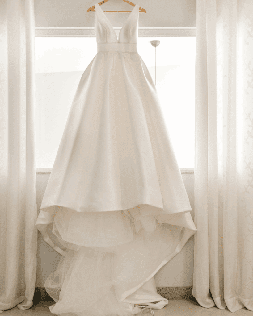 wedding dress on hanger in front of window at destination wedding
