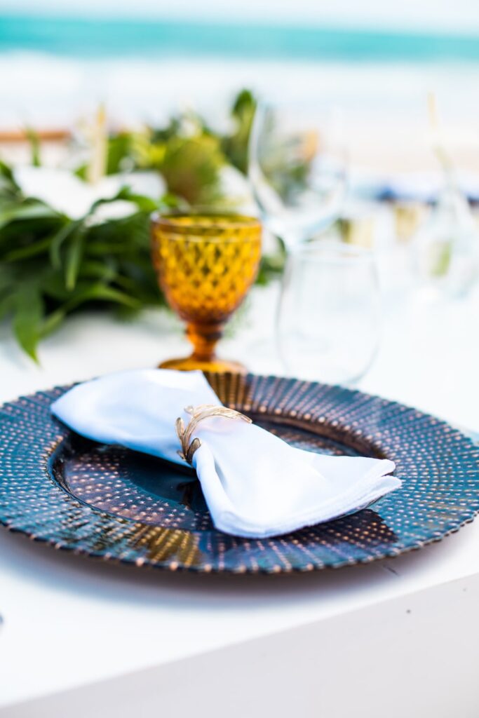 Wood charger plate with white napkin and amber water goblet at wedding place setting