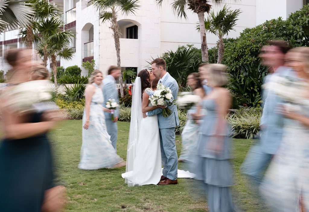 bride and groom kissing surrounded by wedding party