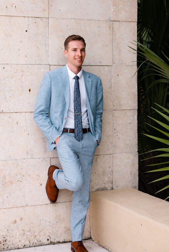 Groom in light blue suite with brown shoes and pattern blue tie