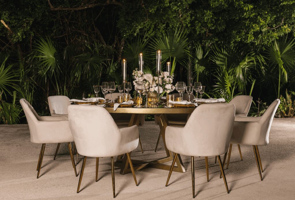 An elegant neutral wedding table with velvet cream chairs, pink flowers and tall candles at an UNICO 20°87° Hotel Riviera Maya wedding reception