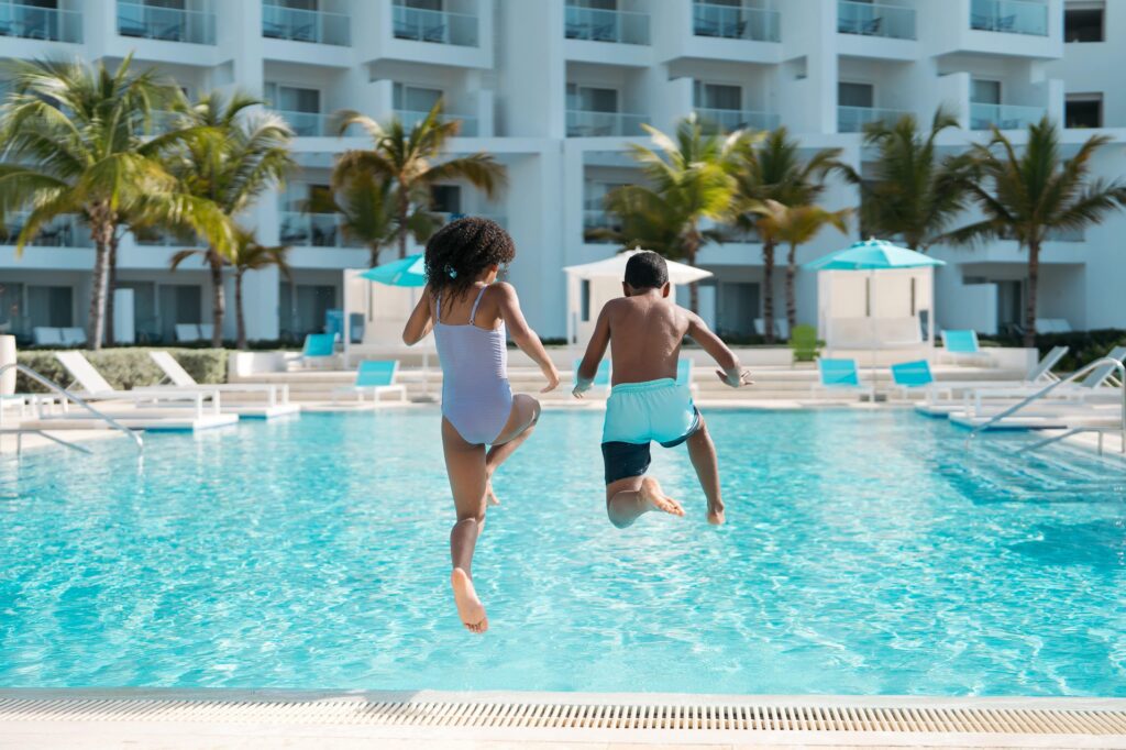 Kids jumping into a pool at a family All-Inclusive resort