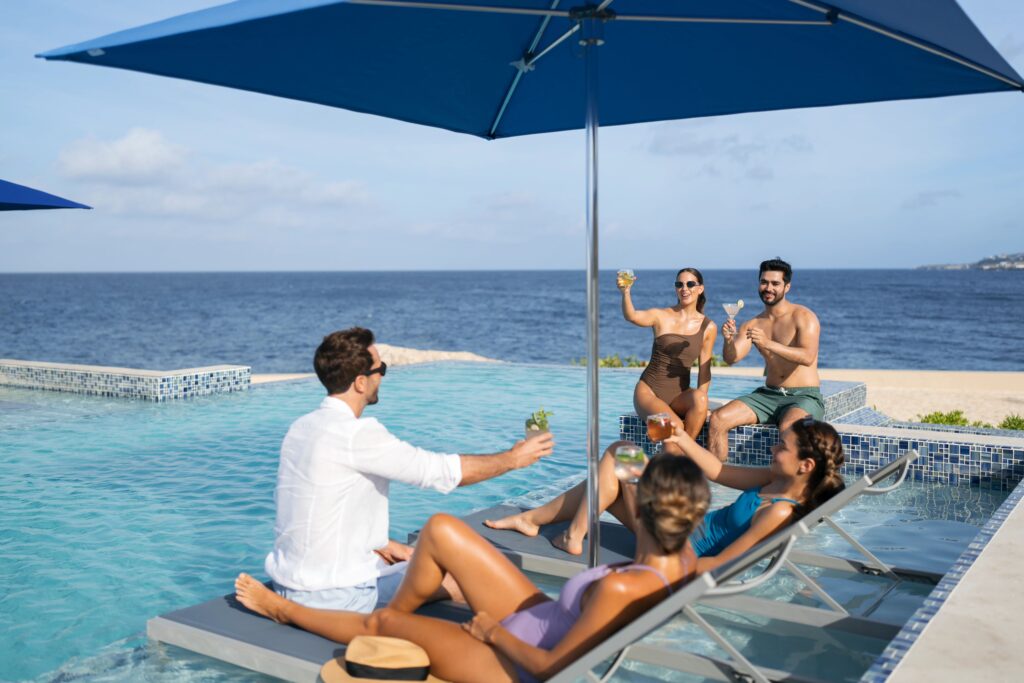 People cheersing drinks in pool loungers