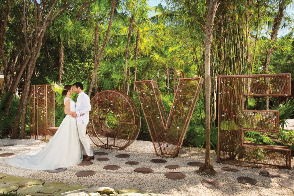 Bride & groom post in front of LOVE sign