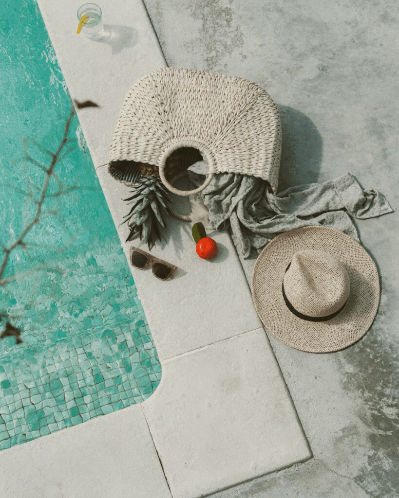 Boho purse with women's travel accessories on the pool deck