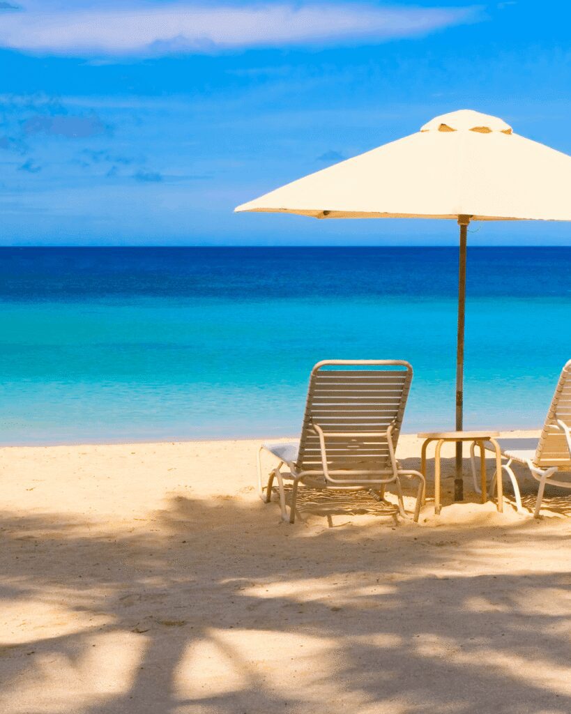 Beach lounge chairs and umbrella by turquoise water Beach lounge chairs and umbrella by turquoise water