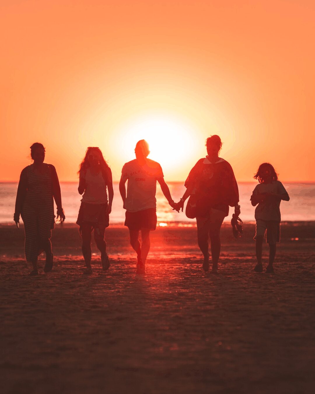 A family walking on the beach in sunset during a group travel trip